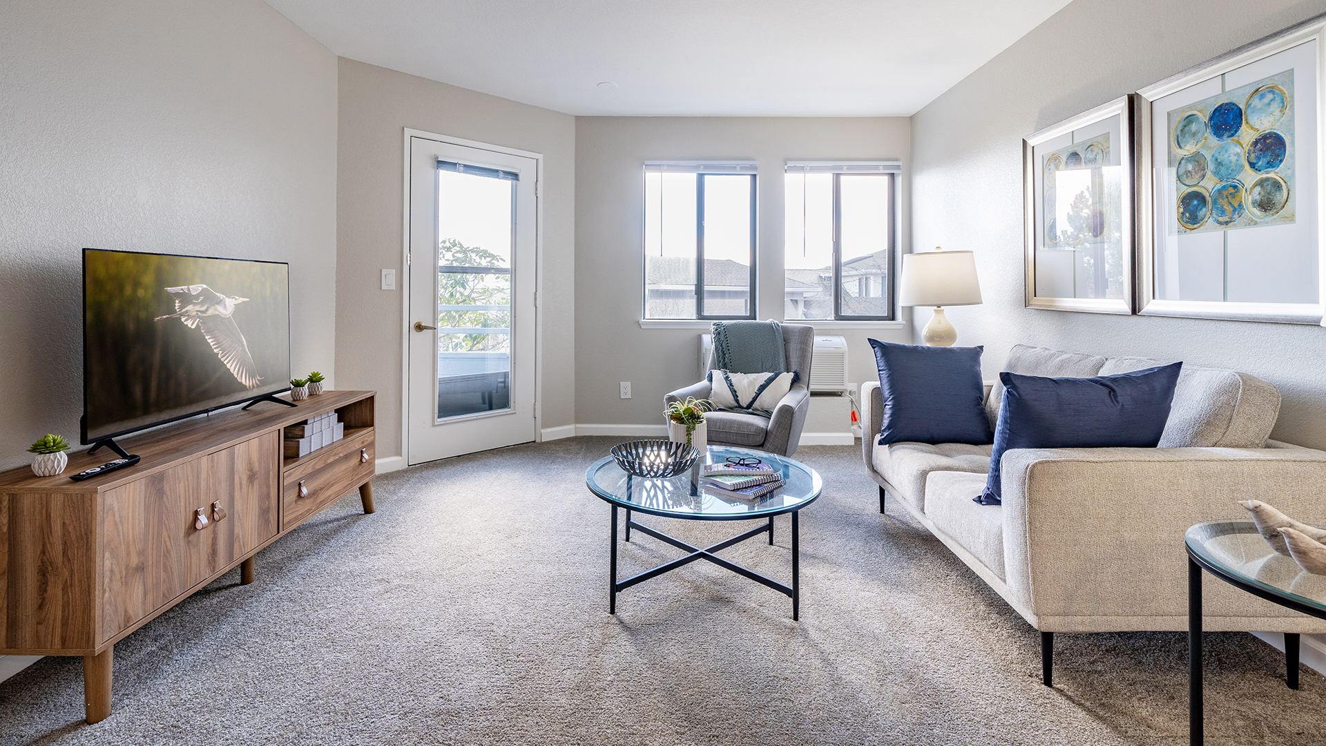 apartment living room model at Holiday Cascadian Place with couch, chair, end tables, coffee table, and entertainment