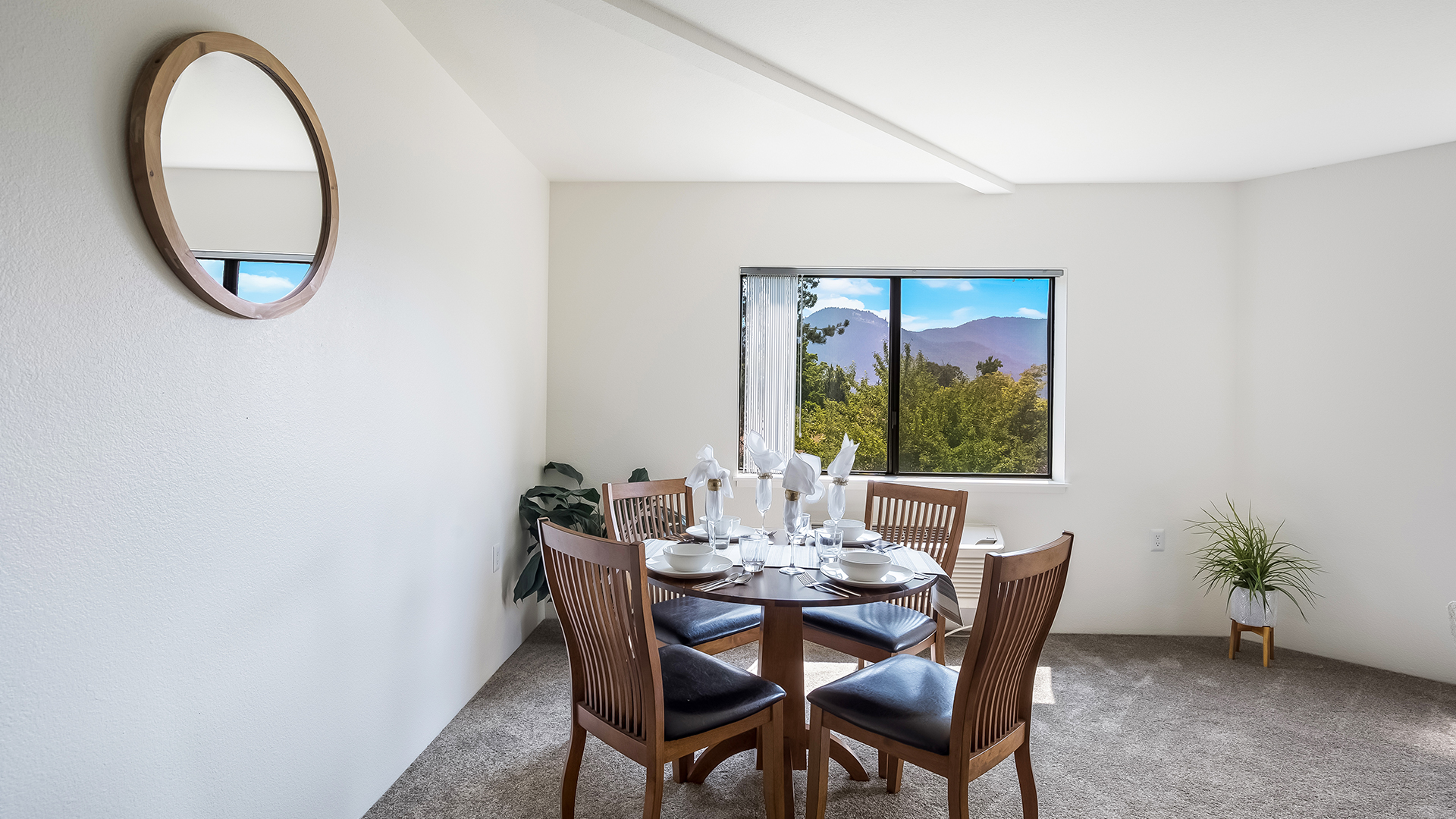 Dining area in front of a window looking at trees and mountains