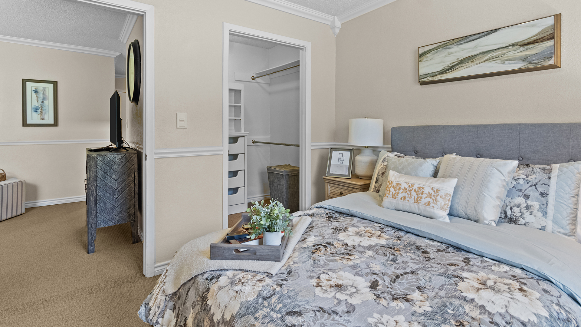 Model apartment bedroom with queen bed, dresser, and large window