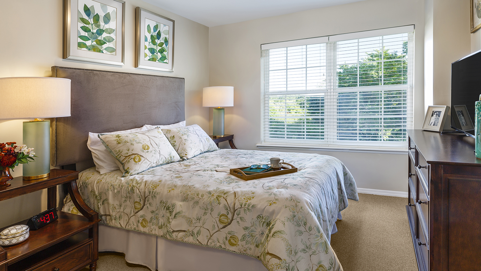 Atria Plainview apartment bedroom with yellow floral bedspread and serving tray on the bed