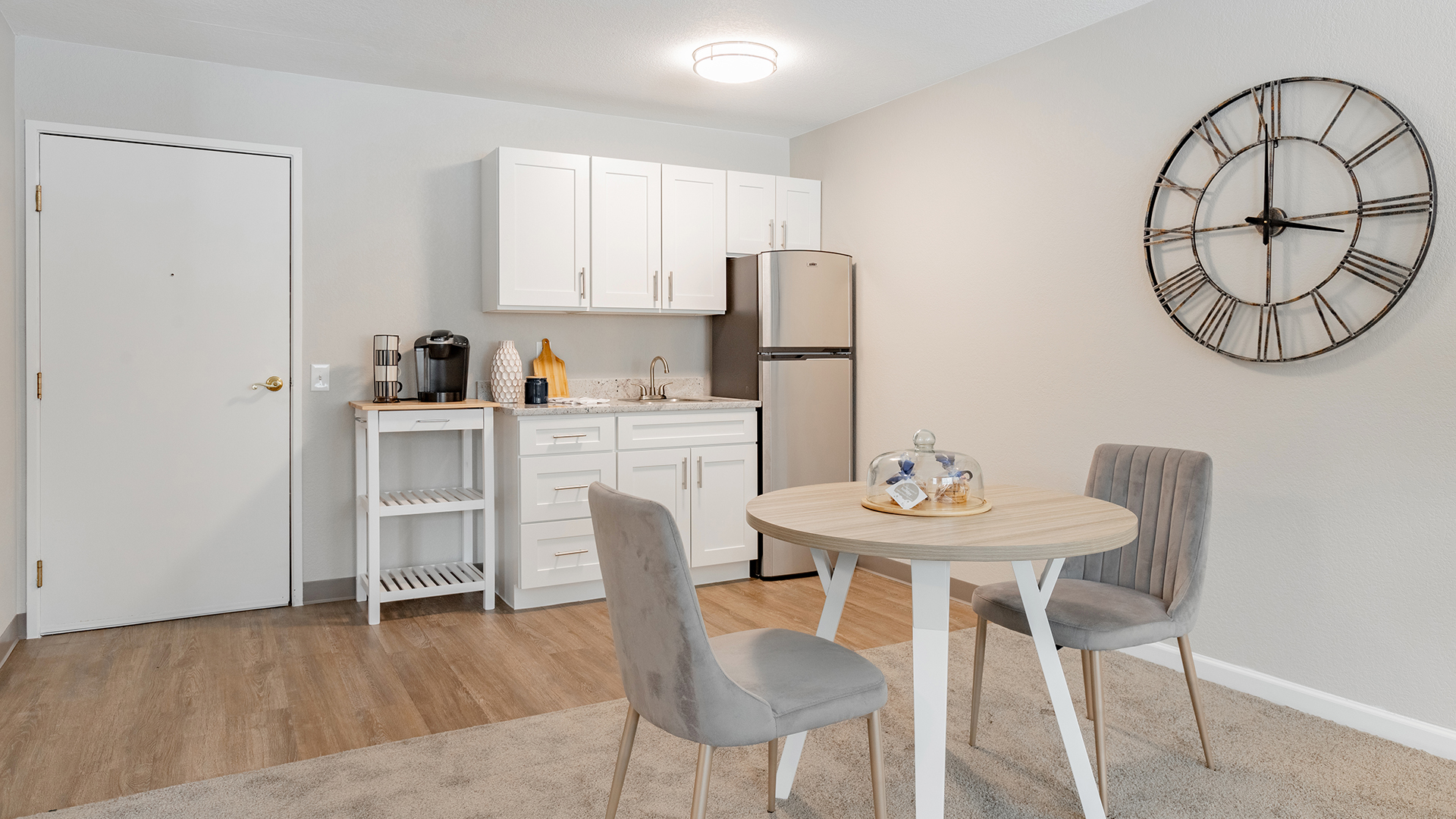 Holiday Parkwood Estates apartment kitchenette with two chair settee, small refrigerator, and cabinets for storage