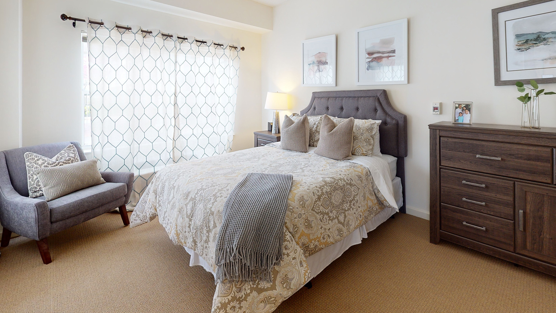 Apartment bedroom featuring a bed with an ornate yellow duvet and bright light