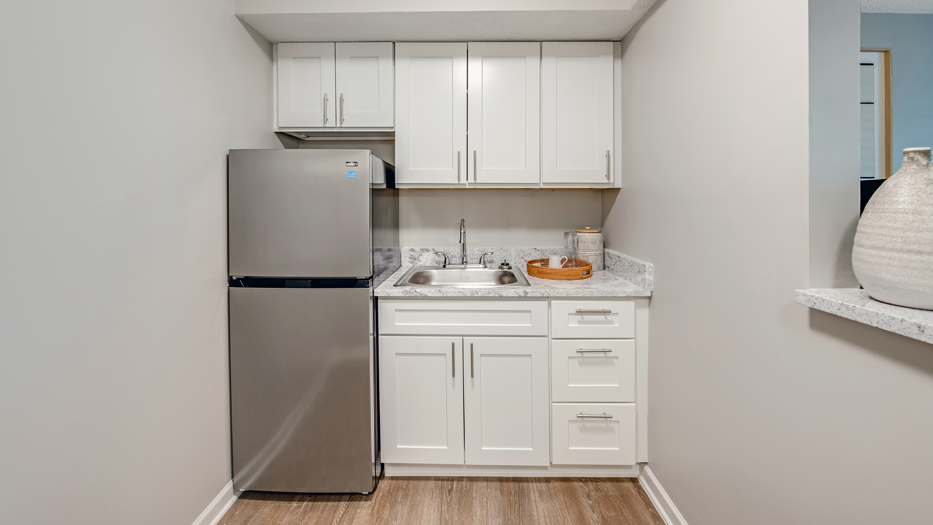 Apartment kitchenette showing fridge and cabinets with a sink