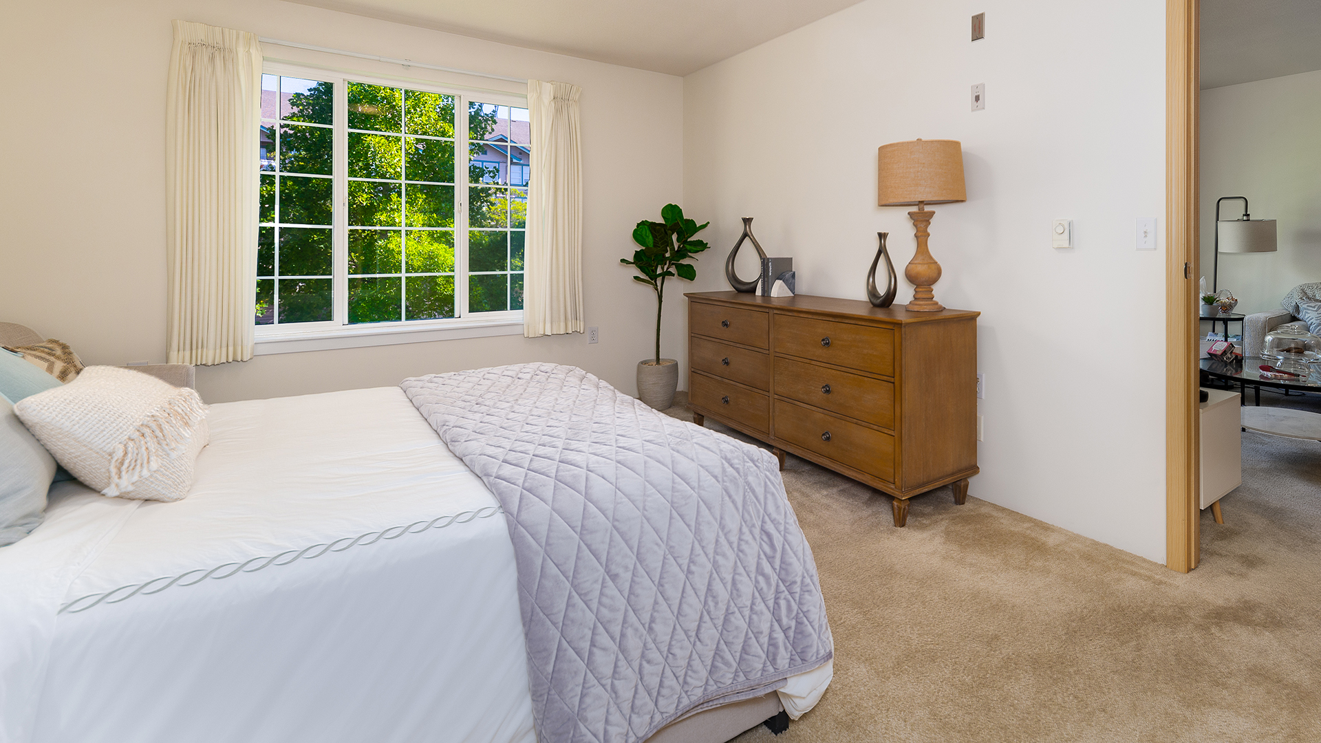 Apartment model bedroom with queen sized bed and full size dresser
